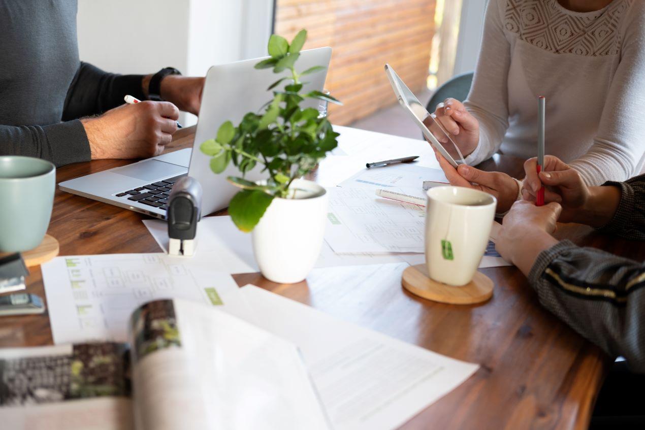 Teamarbeit am Tisch mit Laptop und Dokumenten, Symbol für die Zusammenarbeit mit einer Employer Branding Agentur