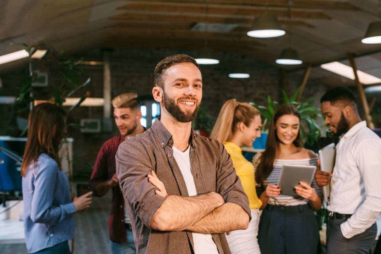 Lächelnder Mitarbeiter in moderner Büroumgebung, unterstützt durch eine Employer Branding Agentur zur Stärkung des Teamgeistes